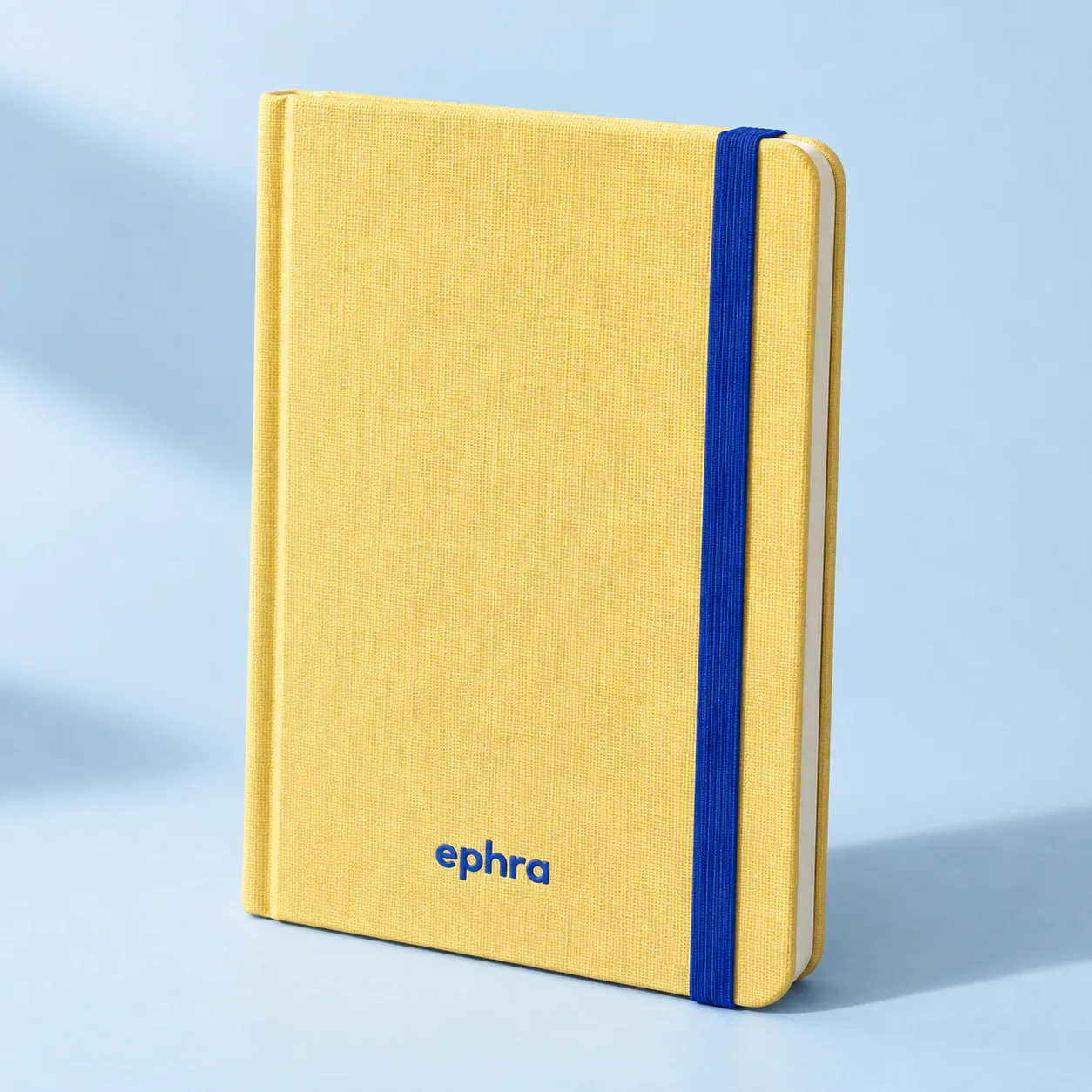 Yellow Ephra pocket notebook with a blue elastic closure. Product concept.