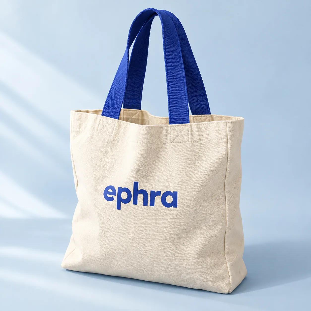 Natural Ephra tote bag with blue handles and wordmark. Product concept.